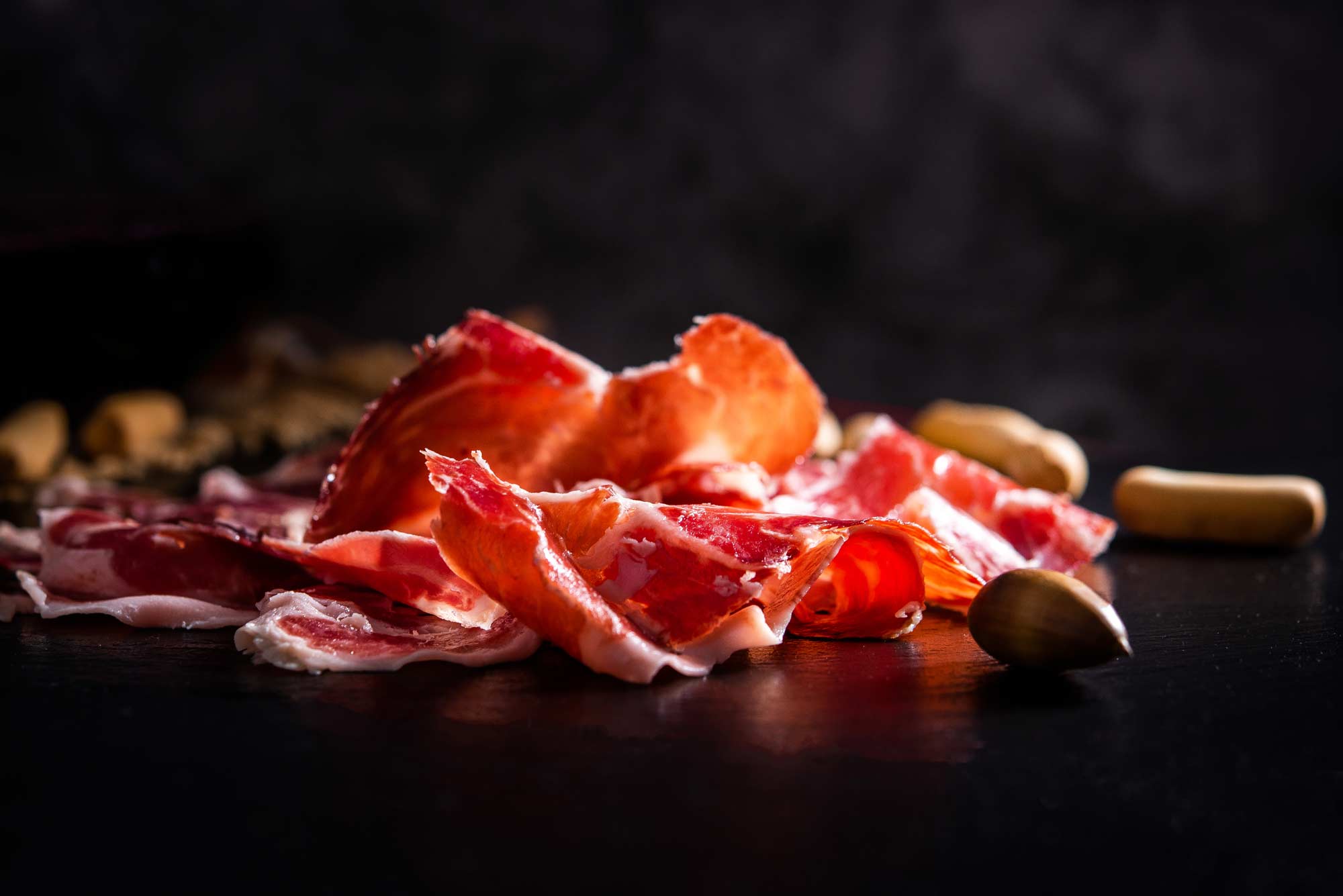 lonchas de jam&oacute;n ib&eacute;rico en primer plano con fondo negro